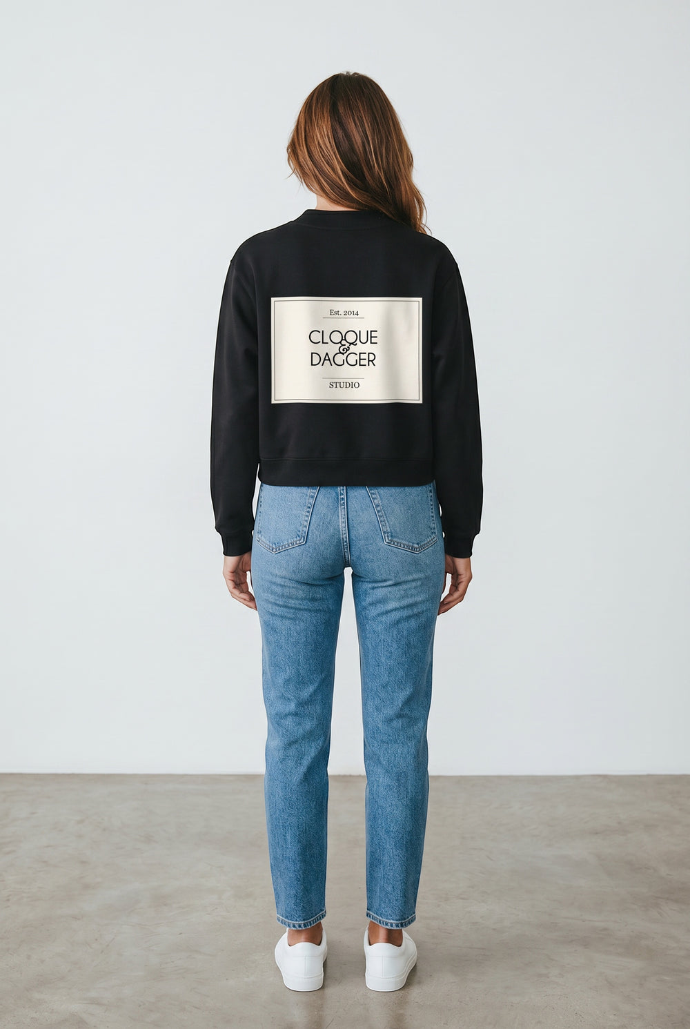 Cloque and Dagger black cotton blend crewneck sweatshirt with mock neck and logo detail on back, worn by a woman in blue jeans.