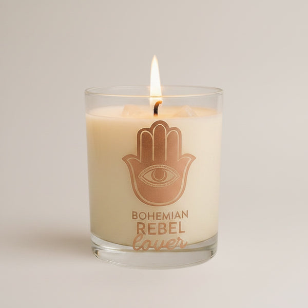 Cloque and Dagger Bohemian Rebel Lover candle in a glass vessel with a Hamsa hand symbol and a lit flame.
