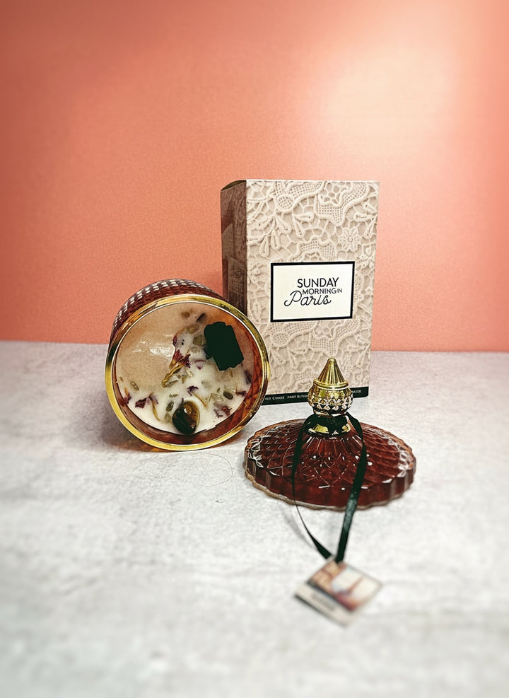 Cloque and Dagger red textured glass candle with gold rim, soy wax, crystals, and botanicals. Lid off.
