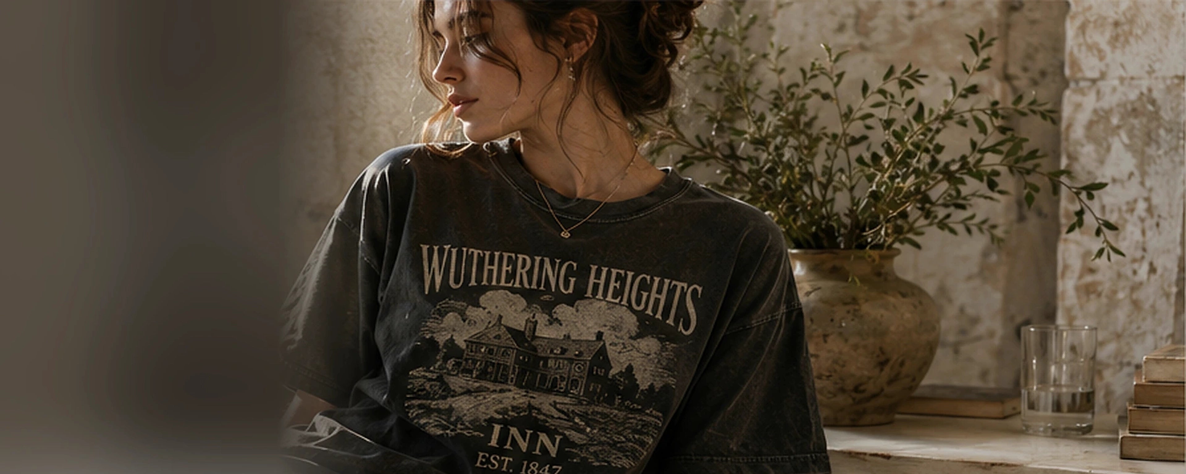 Woman wearing the Wuthering Heights Inn tee in a warm, collected interior